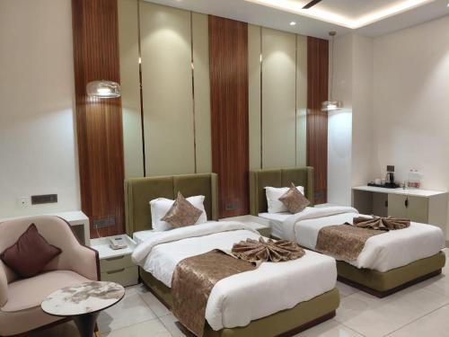 a bedroom with two beds and a chair and a mirror at The Holy Awadh Hotel in Ayodhya