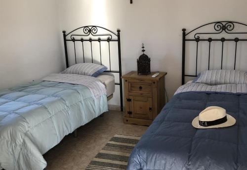 een slaapkamer met twee bedden en een hoed erop bij Cortijo Pura Vida in Cómpeta