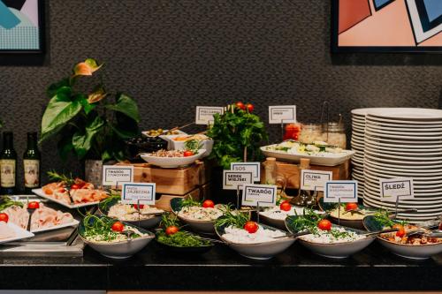 a buffet with bowls of food on a table at Q Hotel Kraków in Kraków