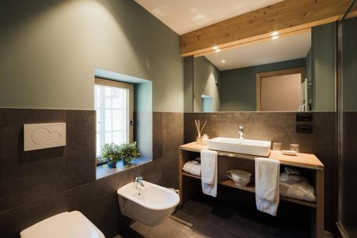 une salle de bain avec un lavabo, des toilettes et un miroir dans l'établissement Berghotel Ladinia, à Corvara in Badia