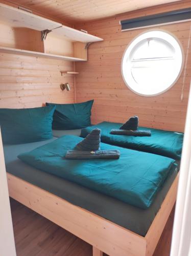a bed in a cabin with a window at Hausboot Smaragd Heiligenhafen in Heiligenhafen