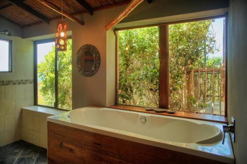 a large bath tub in a bathroom with a window at Tree House Villa in Praia do Tofo