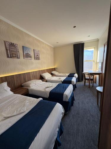 a hotel room with four beds and a table at فندق نزلي المعابدة in Miná
