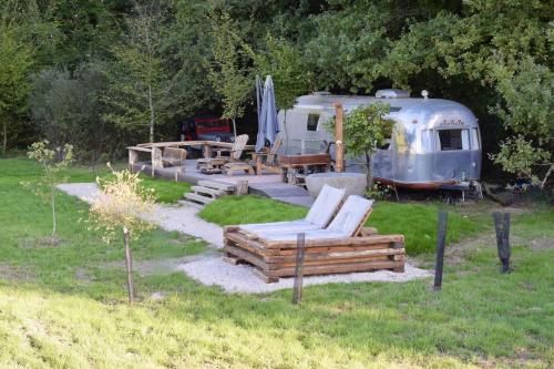 un camping-car garé dans une cour avec des chaises et une table dans l'établissement Red Barn, à Romorantin-Lanthenay