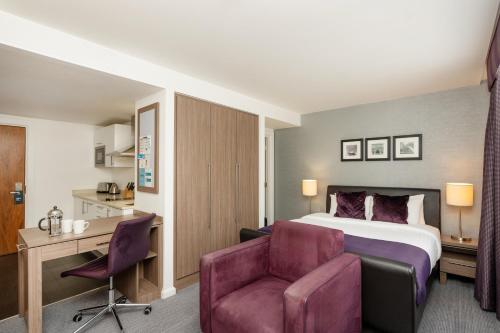 a hotel room with a bed and a desk and a chair at Staybridge Suites Birmingham by IHG in Birmingham