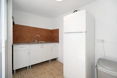 La cuisine blanche est équipée d'un évier et d'un réfrigérateur. dans l'établissement Villa Manuel, à Chiclana de la Frontera