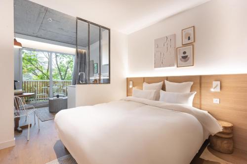 a bedroom with a large white bed and a desk at BABEL COMMUNITY Hôtel Saint-Quentin-en-Yvelines in Montigny-le-Bretonneux