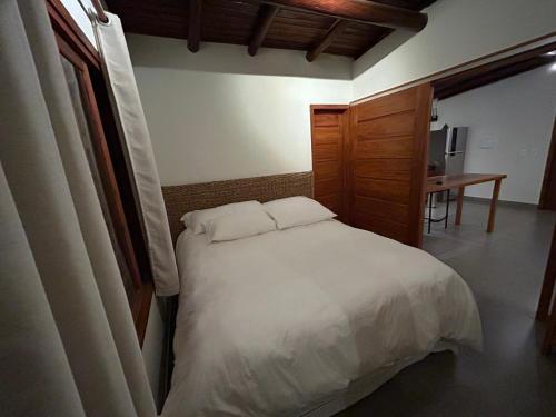Un dormitorio con una cama blanca y un escritorio. en Corumbau Bangalôs, en Prado