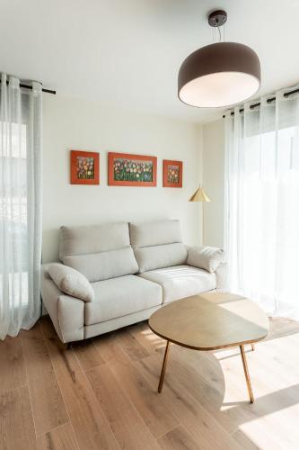 a white living room with a couch and a table at Apartamentos Duratón in San Miguel de Bernúy