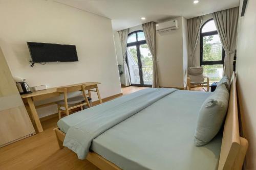 a bedroom with a large bed with a desk and a television at DNh Phu Quoc - Bãi Dài in Phu Quoc