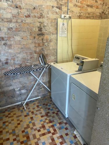 a washer and dryer in a room with a brick wall at Glengarry Castle Hotel in Sydney