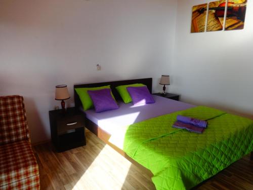 a bedroom with a bed with green sheets and purple pillows at Karali Apartments in Lagadin