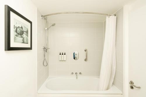 a bathroom with a bath tub with a shower curtain at Staybridge Suites Birmingham by IHG in Birmingham