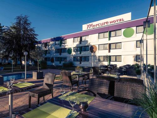 een terras met tafels en stoelen en een hotel bij Mercure Hotel Saarbrücken Süd in Saarbrücken