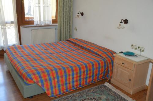 a bedroom with a bed with a plaid blanket at Garní Ladinia in Pescul