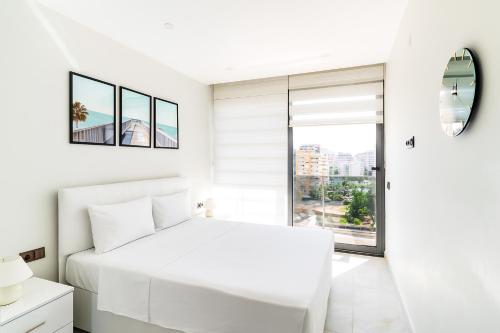 a white bedroom with a white bed and a window at The Blue Tide - 1 Bedroom Apartment - All Bills Included in Alanya