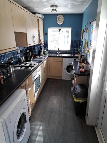Double Ensuite in a colourful quirky terrace on a quiet leafy street في Enderby: مطبخ صغير مع مغسلة وغسالة ملابس
