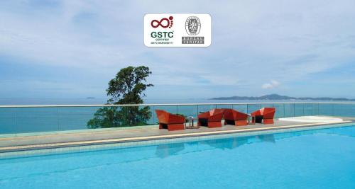 a swimming pool with red chairs next to a building at The Sanctuary Resort Pattaya, BW Signature Collection in Pattaya South