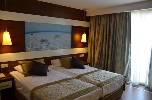 シダにあるHoliday City Hotel-All Inclusiveのベッドと大きな窓が備わるホテルルームです。