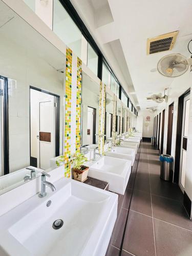 a row of sinks in a bathroom with mirrors at Hotel Sunflower - HLS in Malacca