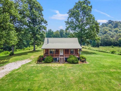 a log cabin in the middle of a field with trees at Heavenly Hideaway - near Red River Gorge KY in Beattyville