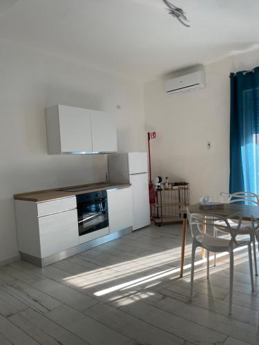 a kitchen with white cabinets and a table and a dining room at Maison appartaments in Bari