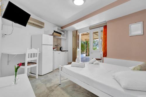 een witte slaapkamer met een wit bed en een keuken bij Tasoula Studio with garden view in Nikiana