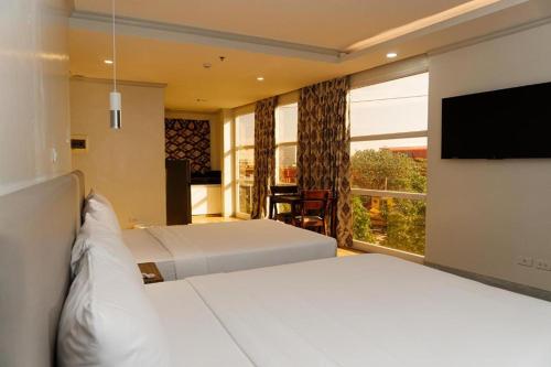 a bedroom with two beds and a flat screen tv at Madison Suites in Lapu Lapu City