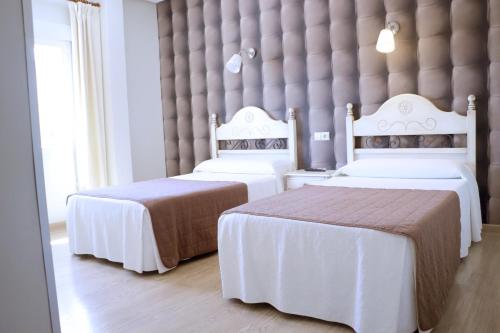 two beds in a hotel room with white sheets at HOSTAL-CAFE GUTGRECO in Sonseca