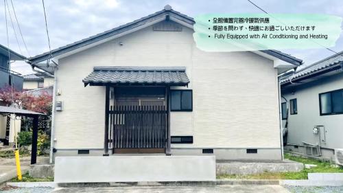 a white house with a gate in front of it at eyehouse ozu No1 in Ozu