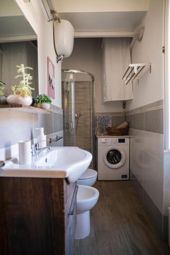 a bathroom with a sink and a toilet and a washing machine at Guest House Little Flower in Sutri