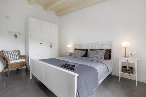 een witte slaapkamer met een groot bed en een stoel bij Ca’ Scaì Agrifugium Elià in Tignale