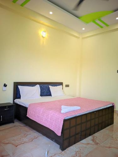 a bedroom with a large bed with a pink blanket at Hotel Pleasure Inn in Prayagraj