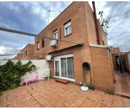 a brick building with a pink chair on a patio at HABITACIÓN en chalet cerca Atocha in Madrid