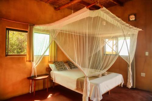 a bedroom with a bed with a canopy at Tree House Cottage, Ocean View in Praia do Tofo