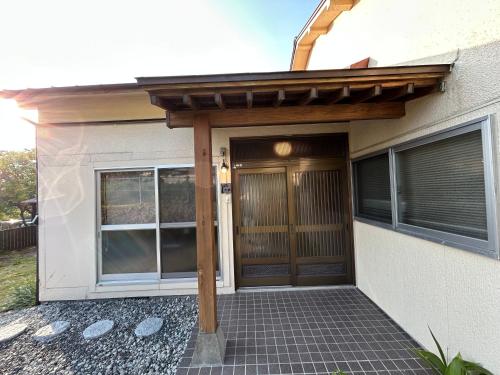 a pergola over a front door of a house at 岳見の宿 天然温泉とプライベートサウナの一棟貸しヴィラ in Yufuin