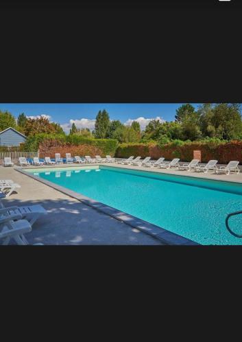 a large swimming pool with lounge chairs at Mobil-home avec grande terrasse in Ivry-la-Bataille