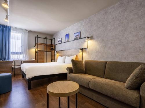 a hotel room with a bed and a couch at IBIS La Rochelle Vieux Port Centre in La Rochelle