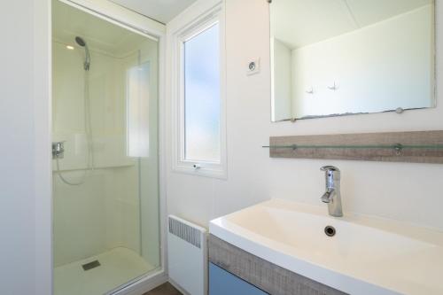 Un baño blanco con lavabo y ducha. en Mobilhome 4-6 personnes, en Argelès-sur-Mer