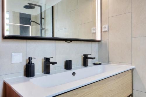 a bathroom with a white sink and a mirror at Le Poinsettia d'Or T3 élégant proche Maïdo & piscine in Le Bois de Nèfles