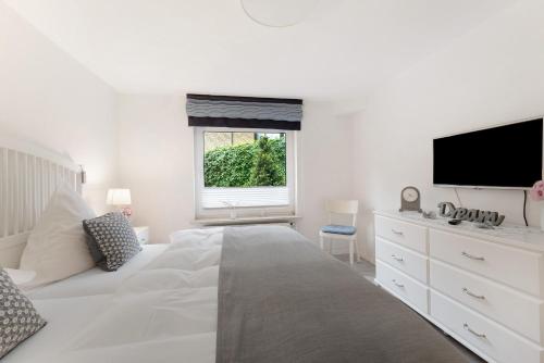 a white bedroom with a large bed and a tv at Ferienwohnung Angeln in Ulstrupfeld