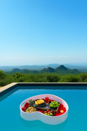 a tray of fruit and wine on a swimming pool at Makgobelo Lodge-The Glass House- Solar powered in Ga-Mokalapa