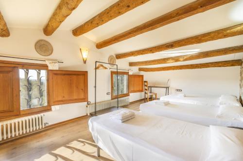 deux lits dans une chambre avec plafonds en bois dans l'établissement Mas Vilardaga, à La Baronia de Rialb