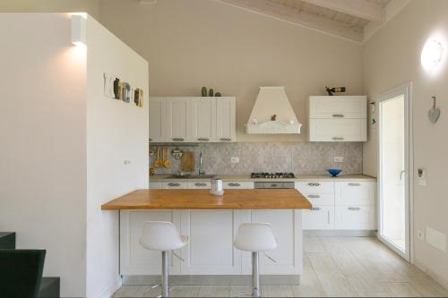 チェチナにあるVilletta Matildeの白いキャビネットと木製のカウンタートップを備えたキッチン