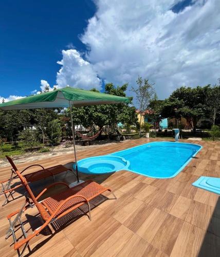ein Swimmingpool mit zwei Stühlen und einem Sonnenschirm in der Unterkunft Chalés Pouso da Coruja in Cavalcante