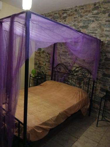 ein Schlafzimmer mit Himmelbett und lila Vorhängen in der Unterkunft Chez André Léon in Ngaparou