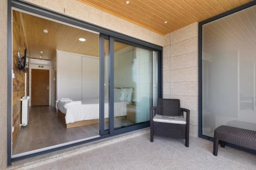 Schlafzimmer mit einem Bett und einem Fenster mit einem Stuhl in der Unterkunft Casa da Marquinhas - Turismo Rural in Lama de Ouriço