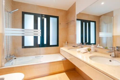un bagno con vasca e un grande specchio di El Oasis Monaco 10 1B a Corverica