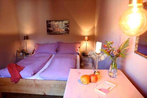 a bedroom with a bed with purple sheets and a table at Luise Im Künstlerhaus in Langmühle