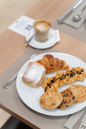 Un plato de pasteles y una taza de café sobre una mesa. en Hotel RH Sorolla Centro, en Valencia